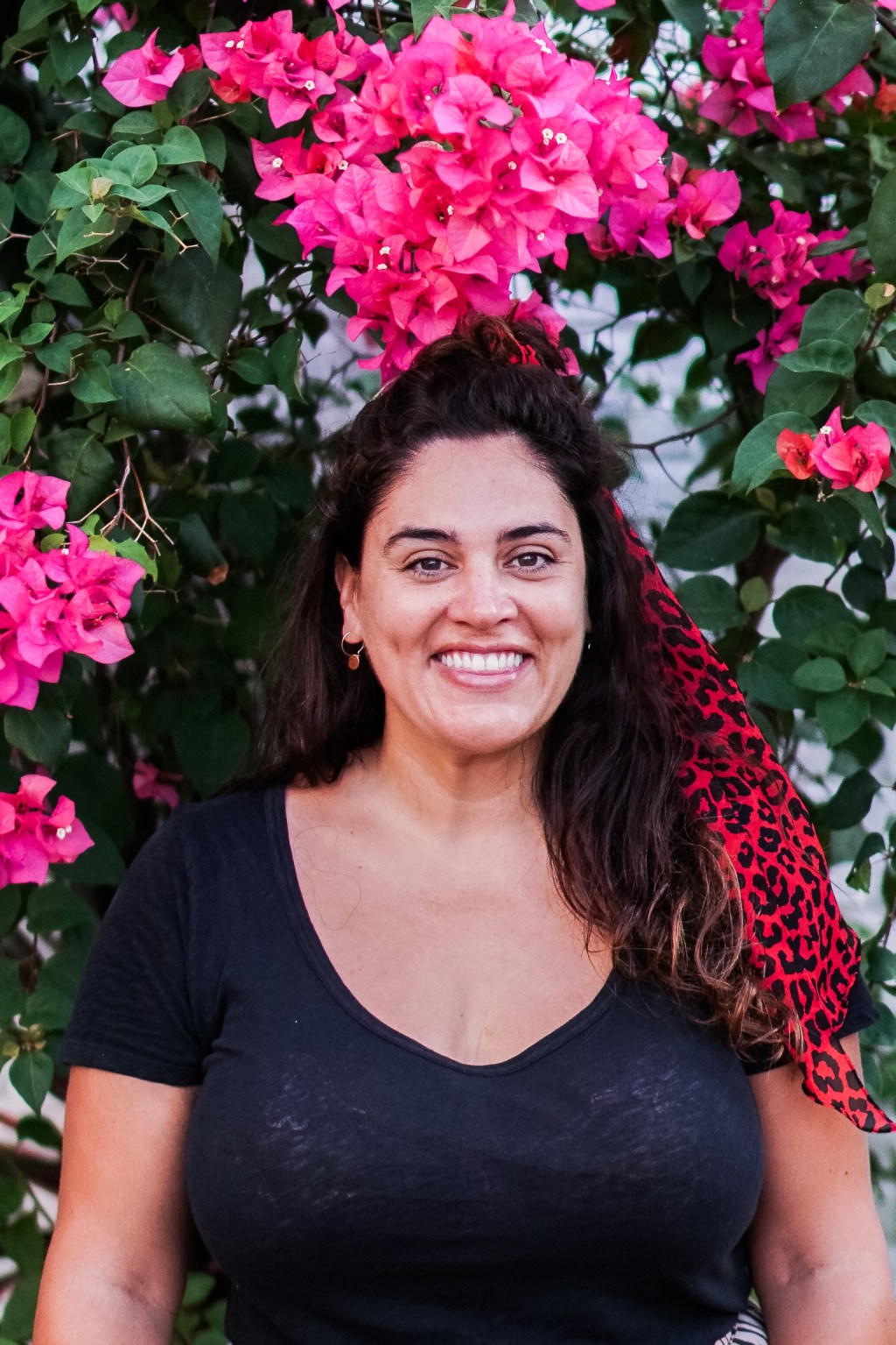 A picture of Jette Virdi, wearing black with pink flowers behind her.